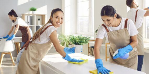 Cleaning company two women smiling posing for camera. Professional cleaning services teamwork with cleaning agent enhancing beauty and hygiene of apartment Team cleans apartment together